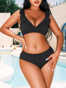 Detail view of black ribbed bikini fabric with elegant ruffle edges and deep V-neckline