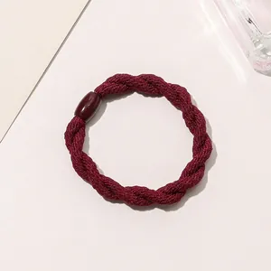 Macro view of burgundy braided hair tie with a decorative resin clasp on light background