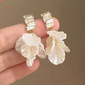 Détail de boucles d'oreilles dorées avec oxydes de zirconium et pétales de fleurs