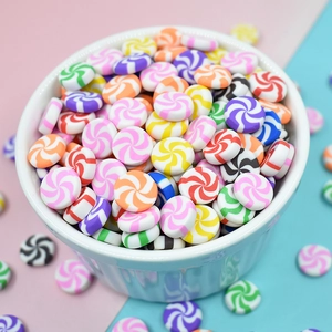 Colorful polymer clay candy charms with spiral patterns in a ceramic bowl for DIY crafts