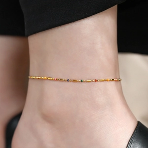 Elegant gold titanium anklet with colorful beads and long tubes on a female ankle