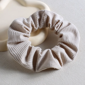 Detail of cream white corduroy scrunchie with soft ribbed texture on tray