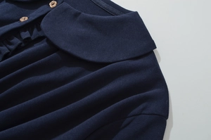 Détail du col bleu marine avec boutons en bois et volants sur une robe en maille