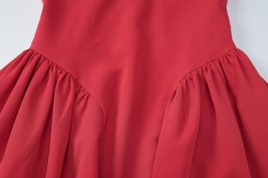 Detailed view of the pleated waistline and fabric texture on a red mini dress