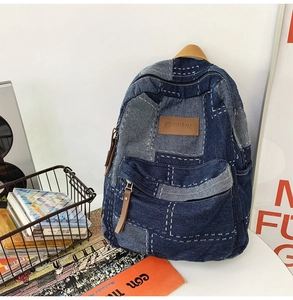Detail view of washed denim patchwork backpack with vintage stitched patterns and logo