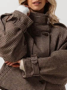 Detail of houndstooth plaid wool coat featuring epaulettes and buttoned cuffs