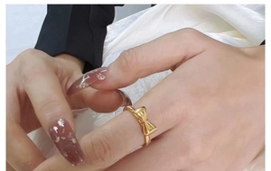 Polished gold bow ring for women shown on a model hand with elegant silk background