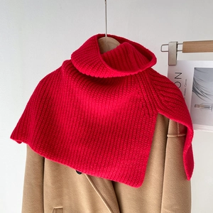 Macro detail of red chunky knit high collar scarf layered on a beige wool coat