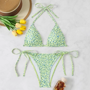 Close-up of floral print bikini with halter top and side-tie bottoms on marble background
