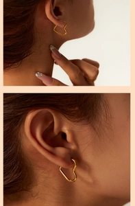 Close-up of minimalist heart-shaped gold earrings worn on ear with high-quality detail