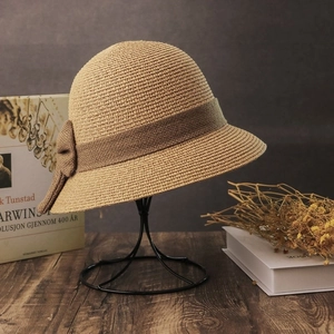 Close-up of a khaki straw sun hat with bow detail on a vintage metal display stand