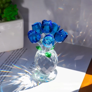 Close-up of six blue crystal roses in a transparent faceted vase with rainbow light reflections