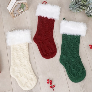 Drei gestrickte Weihnachtsstrümpfe mit Plüschrand auf hellem Holzbodenbelag