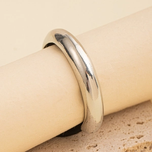 Close-up of minimalist silver metal ring on a beige display with natural stone background