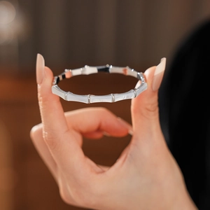 Detailed view of silver bamboo-style bangle featuring elegant white shell-textured inlays