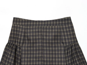 Detailopname van de tailleband en plooien op de bruine geruite minirok voor dames