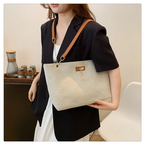 Minimalist beige nylon tote bag with brown leather handles and golden deer charm