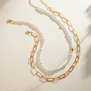 Double-layered gold rectangle link chain and white pearl necklace with a gold heart bead
