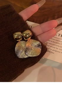 Détail de boucles d'oreilles dorées avec pendentifs ovales à texture martelée