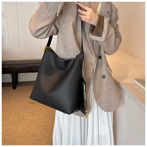 Detail of black pebbled leather tote bag with gold hardware and matching coin purse charm