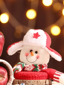 Nahaufnahme eines Plüsch-Schneemanns mit rotem Sternenhut und gemütlichem Strickschal