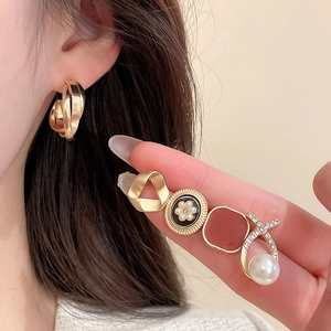 Detailed close-up of mixed pearl and rhinestone earrings with gold plating and enamel