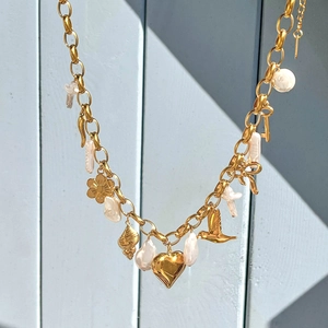 Gros plan détaillé d'un collier doré avec perles baroques et pendentifs cœurs