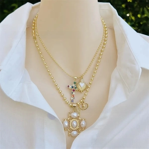 Detailed close-up of a layered gold-plated necklace set with cross and heart charms