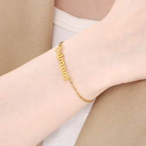 Macro shot of gold-plated mama script bracelet with diamond accents on a female wrist