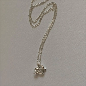 Macro detail of silver knot pendant necklace with a single diamond stone inlay