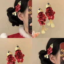 Dettaglio accessorio per capelli a forma di pesce con paillettes rosse e finiture dorate