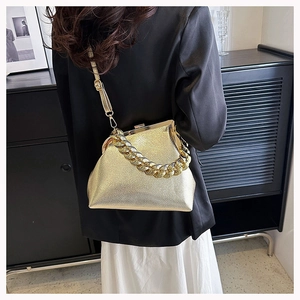 Detail view of gold textured frame bag featuring a chunky chain handle and leather strap