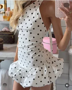 Détail d'une robe blanche à pois asymétrique avec ourlet à volants et taille ajourée