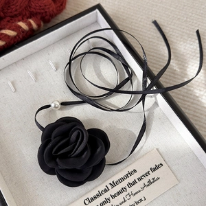 Detail of a vintage black fabric rose choker with pearl accents in a gray gift box