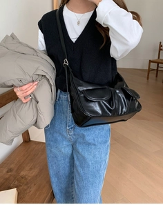Detail of a chic black baguette bag with front pockets styled in a casual street fashion look