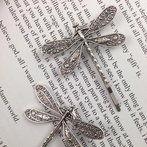Vintage silver dragonfly hair clip set with intricate filigree details on literary paper