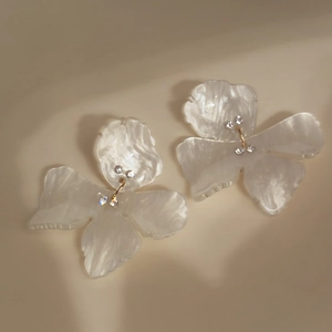 Detailed view of pearlescent floral earrings with resin petals and shimmering crystals