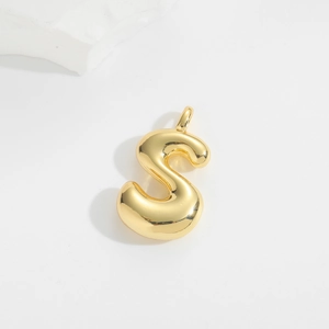 Macro shot of a puffy golden metal letter S balloon pendant with polished finish
