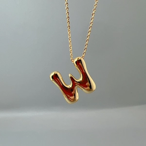 Detailed view of a gold initial W pendant with a sleek polished metallic finish on a fine chain