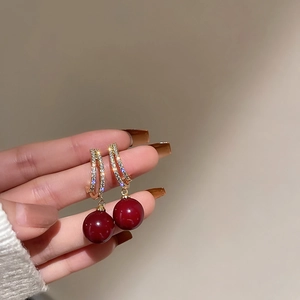 Close-up of deep red pearl drop earrings with sparkling rhinestone arches