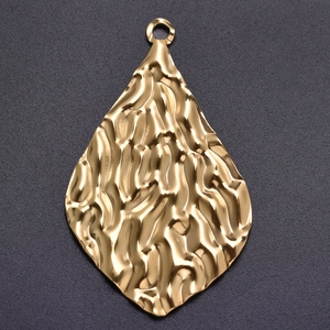 Macro view of gold stainless steel teardrop pendant with hammered texture detail