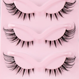 Dramatic fox-eye false eyelashes with clear bands and wispy volume on a pink tray