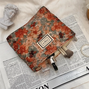 Close-up of corduroy floral makeup bag with metal zipper and beauty accessories inside