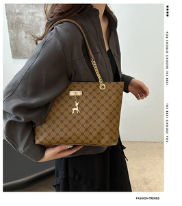 Brown tote bag with geometric pattern and golden deer charm on metal chain strap