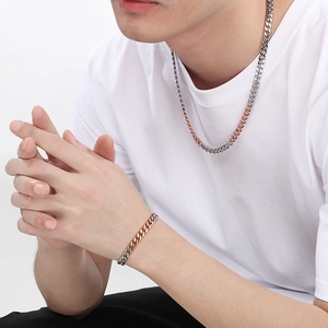Close-up of two-tone silver and rose gold stainless steel Cuban link necklace and bracelet