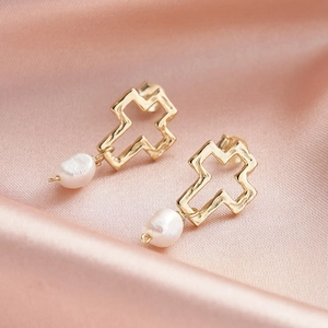 Détail des boucles d'oreilles croix en argent S925 avec perles sur fond de soie