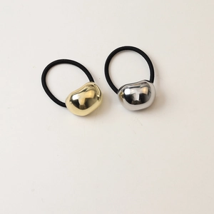 Detail view of gold and silver bean-shaped metallic hair ties on black elastic bands