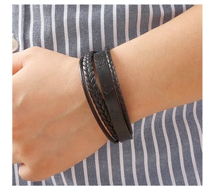 Detailed close-up of multi-layer black braided leather bracelet worn on male wrist