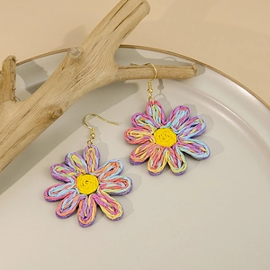 Gros plan de boucles d'oreilles marguerites tissées à la main aux pétales colorés