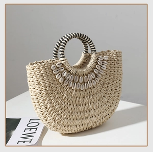 Detail of handmade straw bag featuring natural cowrie shell embellishments and a striped handle